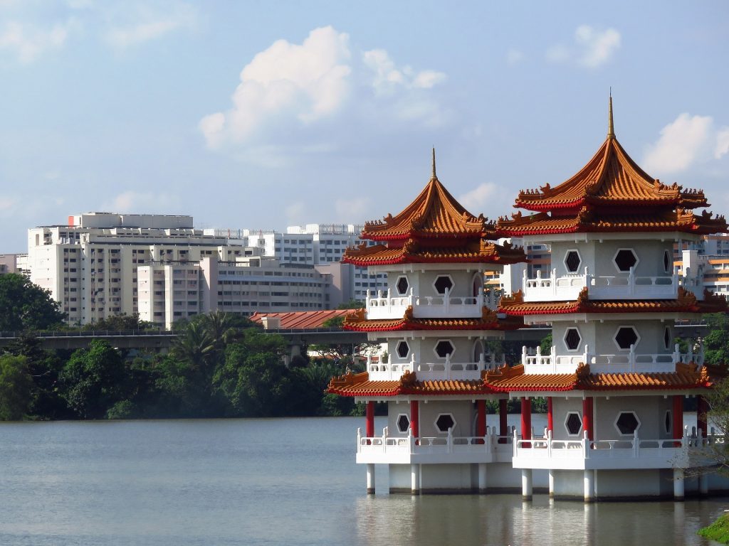 Twin Chinese pagodas on water contrasts with a modern cityscape in the background