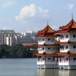 Twin Chinese pagodas on water contrasts with a modern cityscape in the background